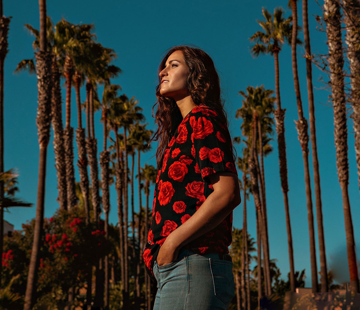 Angie K standing in front of palm trees and a blue sky.
