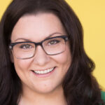 Jessi Campbell wearing glasses and smiling with a yellow background.