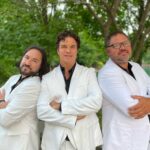 Brothers Gibb band members in white suits with black button downs underneath.